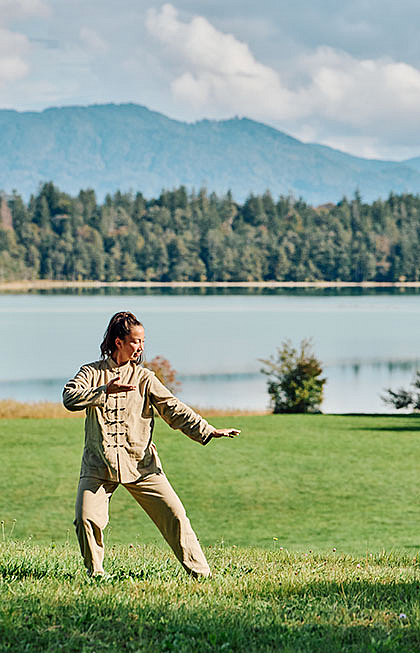 Qigong in freier Natur mit Blick über See und Berge.